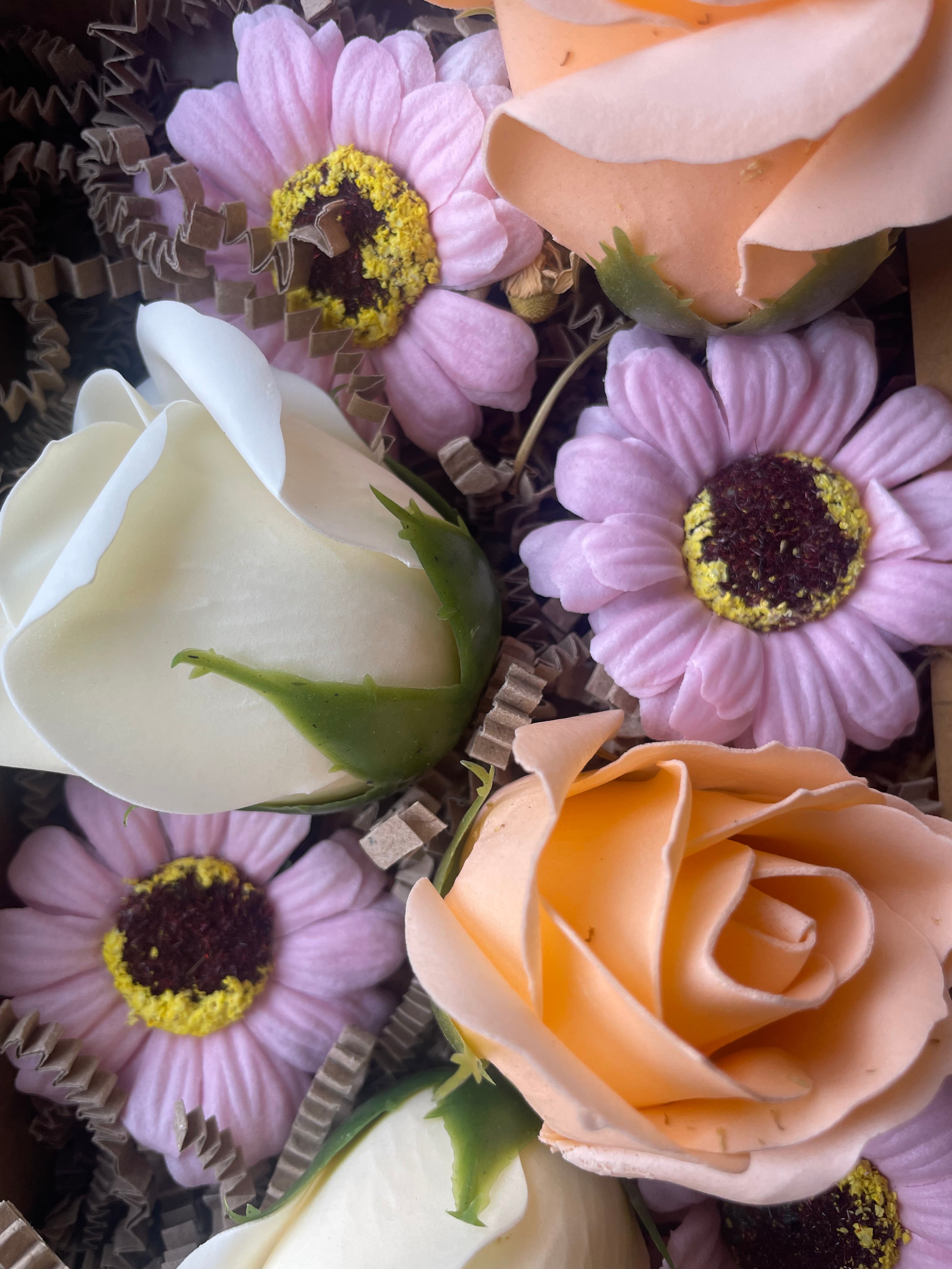 Close-up of artificial flowers including roses and daisies on a textured surface.