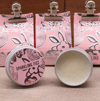 Two tins of lip balm, with pink lids labeled 'Sparkling Fizz' and 'Agnes + Cat' branding, with pink boxes in the background.